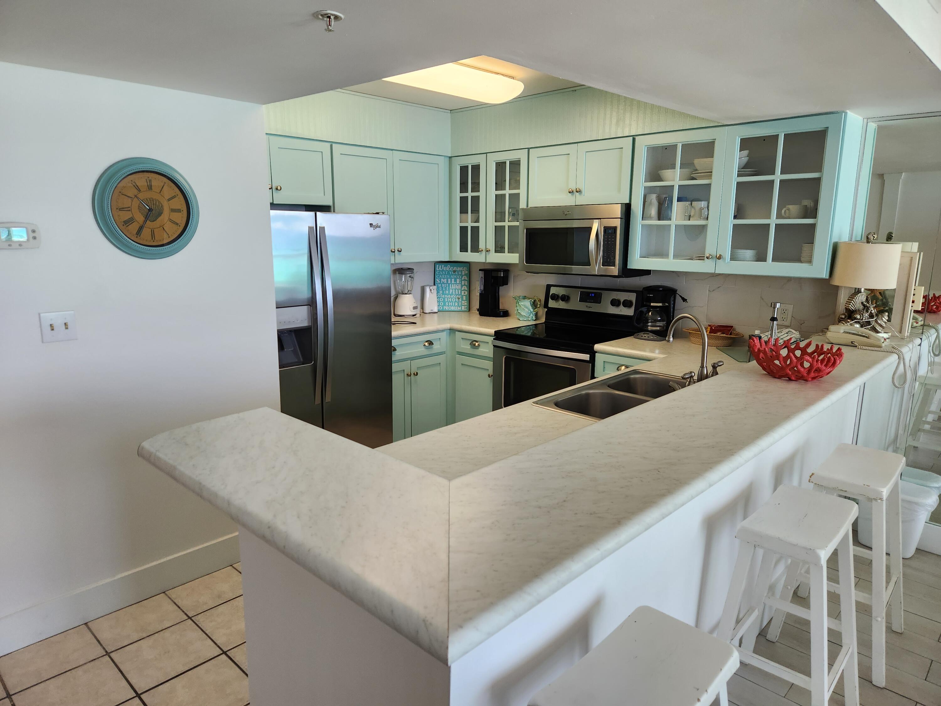 1002 Highway 98, Unit 505 Destin, FL 32541 - Photo 5 of 17 a kitchen with stainless steel appliances granite countertop a sink refrigerator stove and microwave