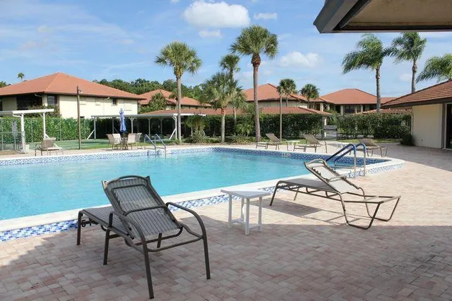 a view of a swimming pool with lawn chairs under an umbrella