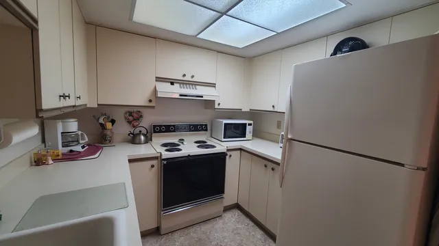 a view of a kitchen with fridge and wooden floor