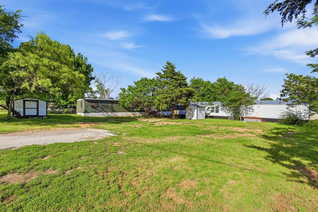 316 Summit Drive Springtown, TX 76082 - Photo 2 of 39 The property features an extensive green lawn, mature trees, and a gravel pathway