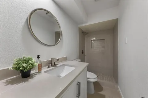 a bathroom with a granite countertop sink a toilet and a mirror
