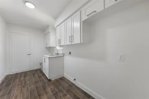 a room with a white wooden floor and white cabinets