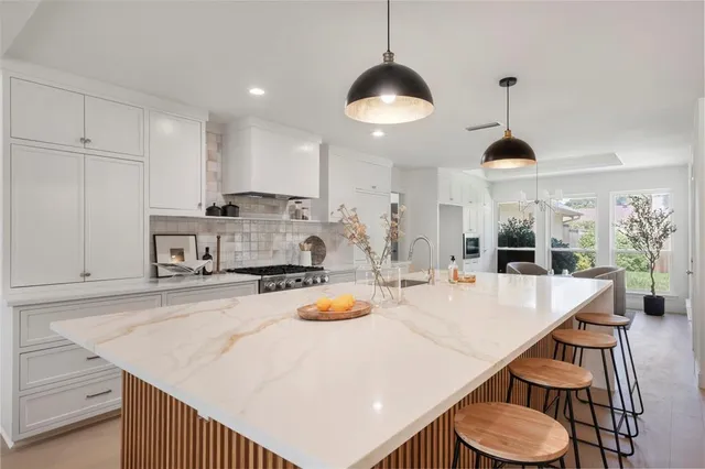 a kitchen with stainless steel appliances granite countertop a sink a stove and chairs
