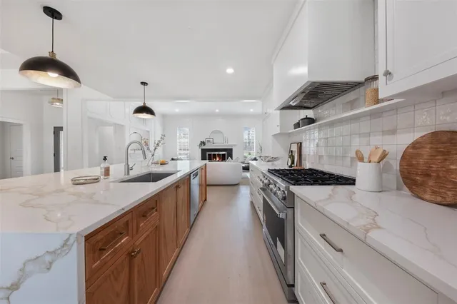 a kitchen with stainless steel appliances granite countertop a sink a stove and a wooden floors