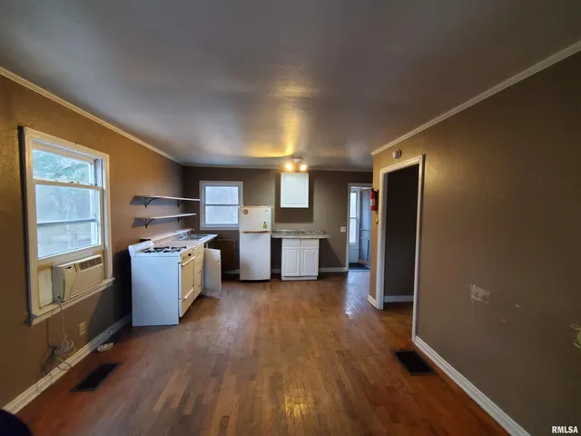 a kitchen with refrigerator and wooden floor