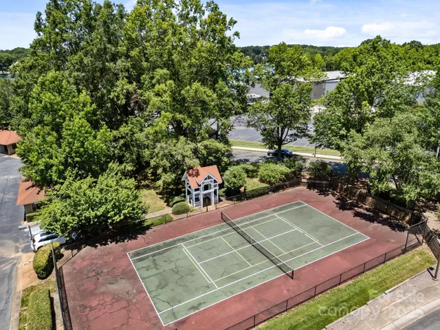 a view of a tennis ground with large trees