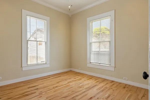 an empty room with wooden floor and windows
