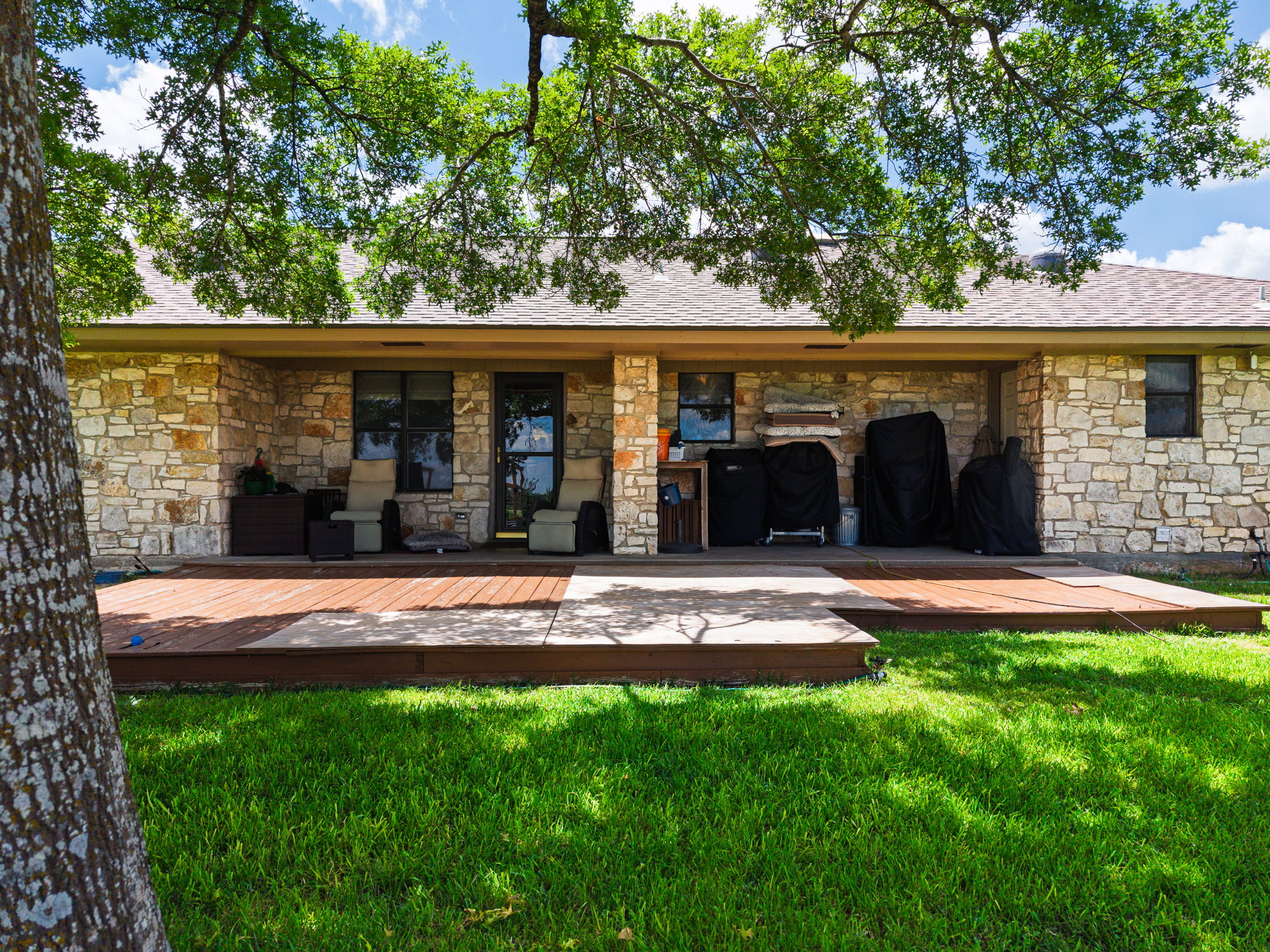 120 Rae Lane Jarrell, TX 76537 - Photo 27 of 40 Stone-clad rear exterior featuring a covered patio, multi-level wood deck, and a manicured lawn
