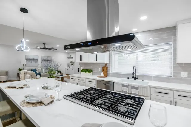 a kitchen with kitchen island granite countertop a sink stove and white cabinets