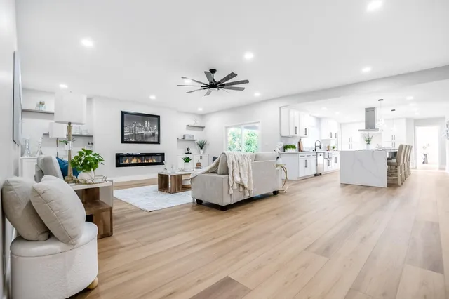 a living room with furniture and a large window with kitchen view
