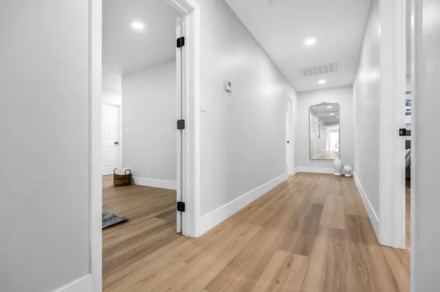 a view of a hallway with wooden floor and a bathroom