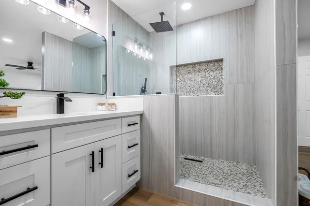 a bathroom with a sink a mirror a vanity and shower