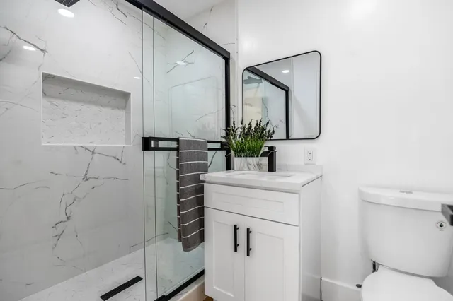 a bathroom with a granite countertop sink toilet and shower