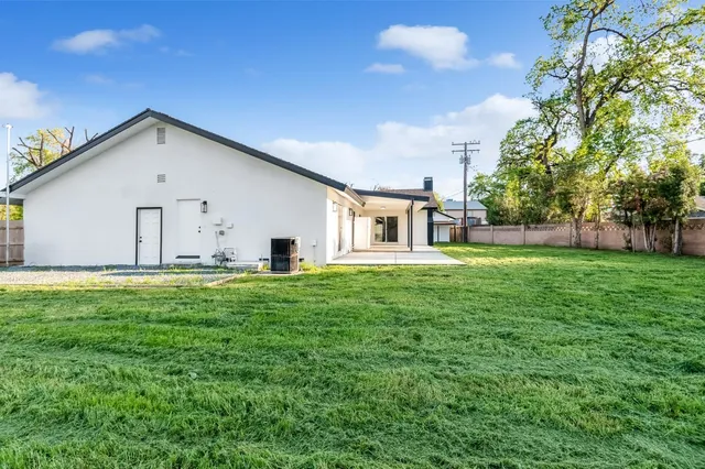 a backyard of a house with table and chairs plants and large tree