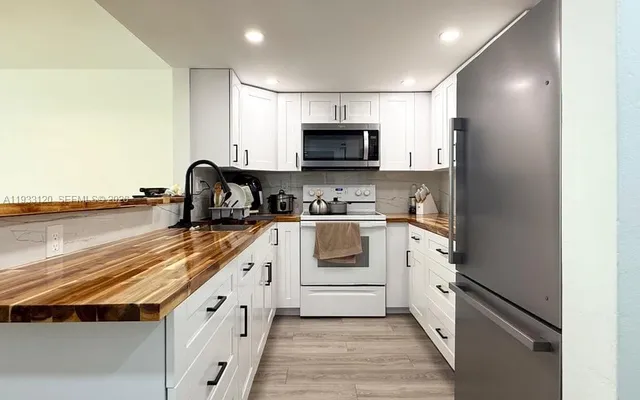 a kitchen with stainless steel appliances granite countertop a stove a sink and a microwave