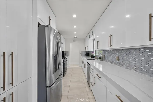 a large kitchen with a large counter top stainless steel appliances and cabinets