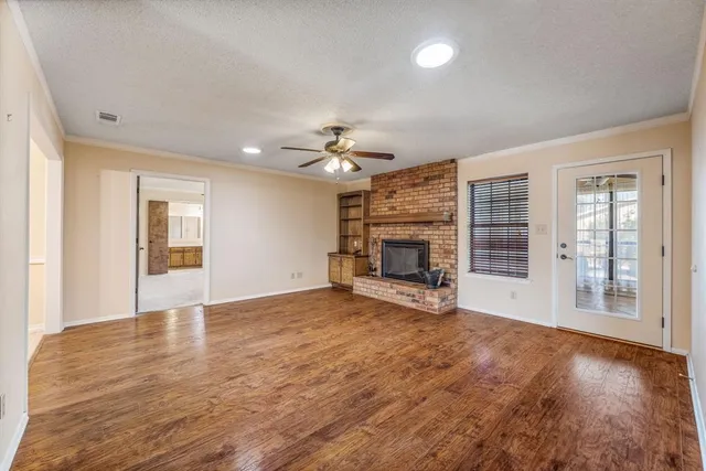 a view of an empty room with wooden floor and a fireplace