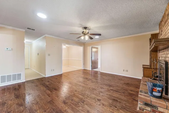 a view of an empty room with window and wooden floor