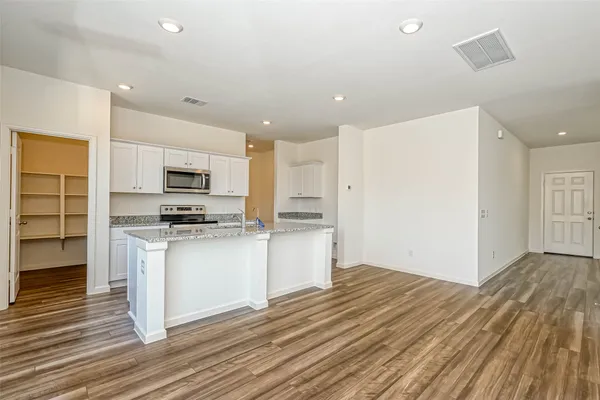 a kitchen with wooden floor and electronic appliances