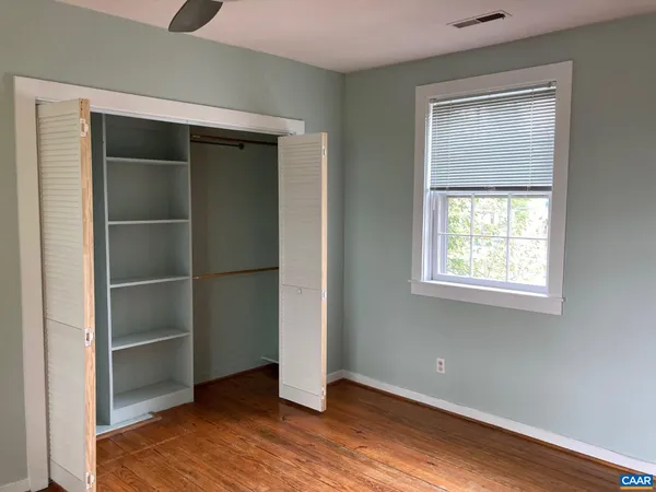 a view of an empty room with closet and a window