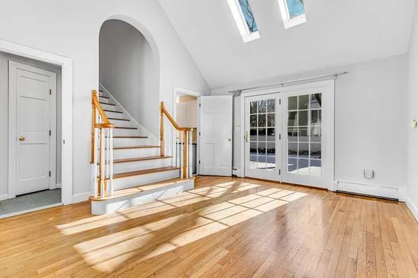 a view of an empty room with wooden floor and stairs