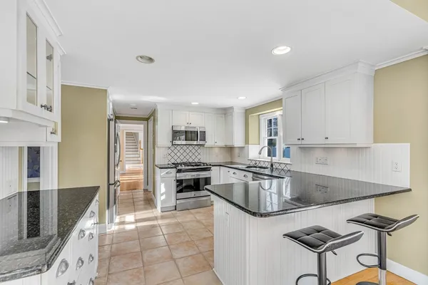 a kitchen with stainless steel appliances granite countertop a stove top oven a sink a refrigerator and white cabinets