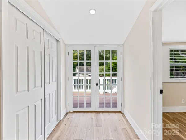 a view of an empty room with wooden floor and a window