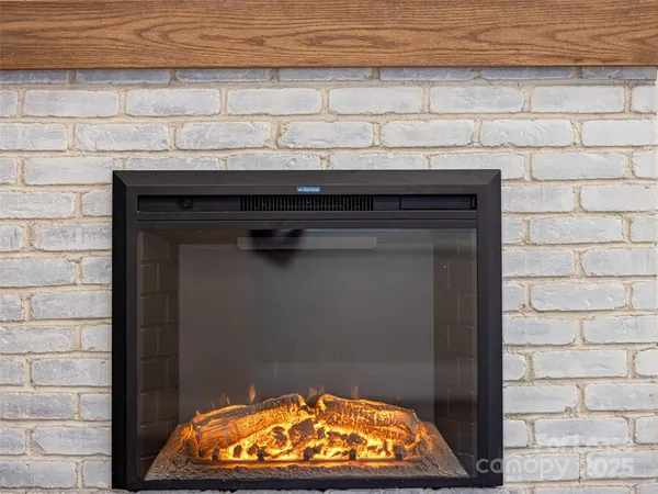 a view of an empty room with wooden floor fireplace and a window