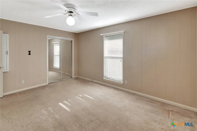 an empty room with windows and fan
