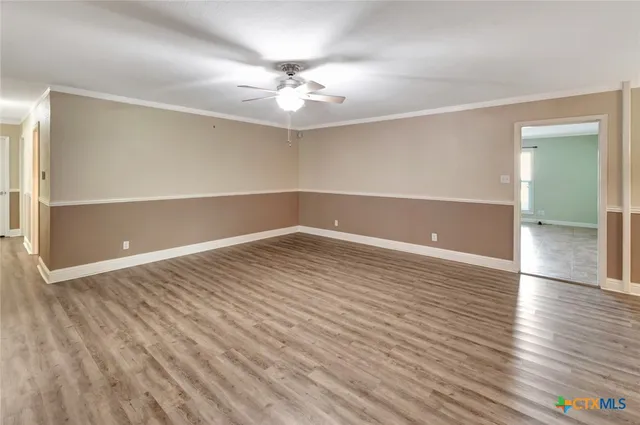 an empty room with wooden floor and fan
