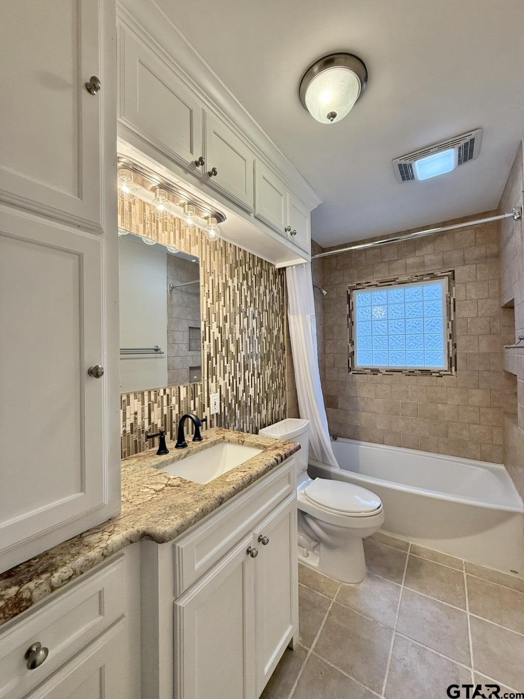 603 Wilma Street Tyler, TX 75701 - Photo 14 of 26 a bathroom with a granite countertop sink a toilet a mirror and bathtub