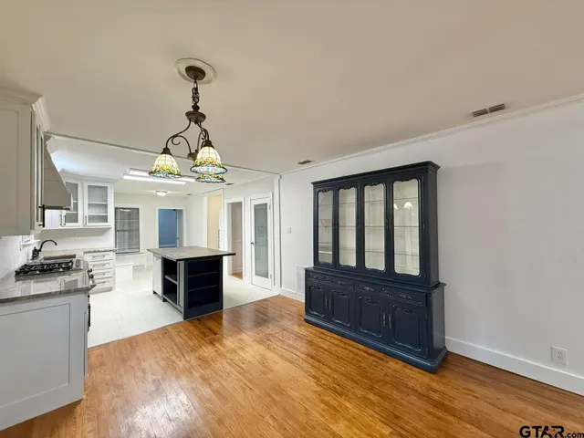 a view of a livingroom with wooden floor and a kitchen space