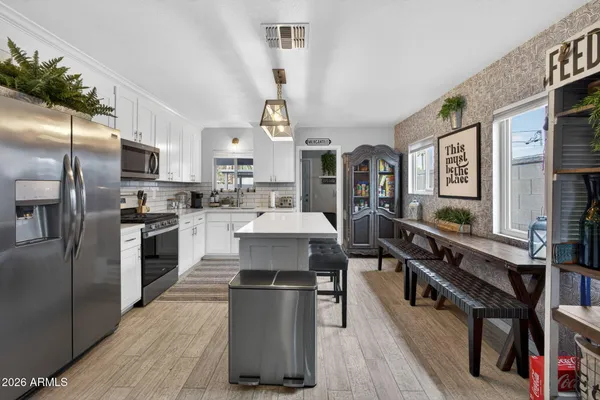 a kitchen with stainless steel appliances a stove a sink dishwasher a refrigerator white cabinets with wooden floor and dining table