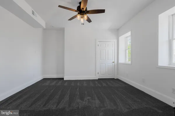 a view of room with hardwood floor and a ceiling fan