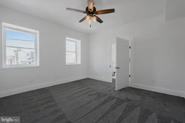 an empty room with fan and windows