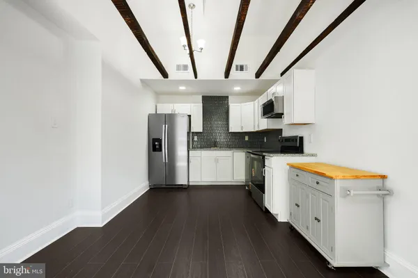 a kitchen with stainless steel appliances granite countertop a refrigerator a sink dishwasher a stove and white countertops with wooden floor