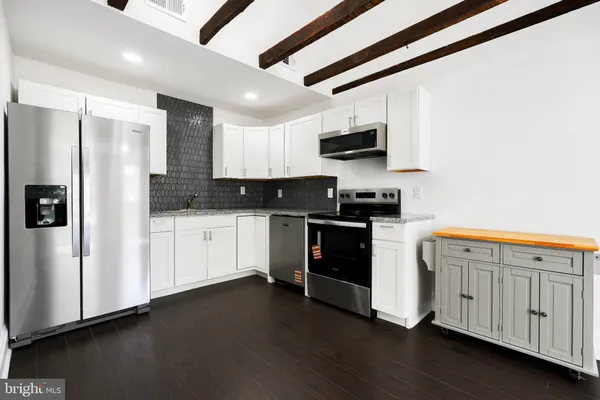 a kitchen with granite countertop white cabinets and stainless steel appliances