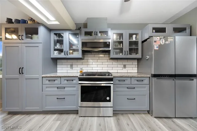 a living room with stainless steel appliances kitchen island furniture and a wooden floor