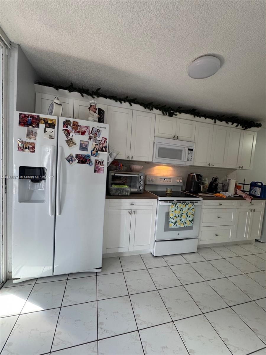 2410 Southwest 122nd Court, Unit 1 Miami, FL 33175 - Photo 8 of 26 a kitchen with a refrigerator and cabinets