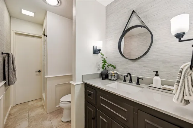 a bathroom with a granite countertop sink a toilet and a mirror