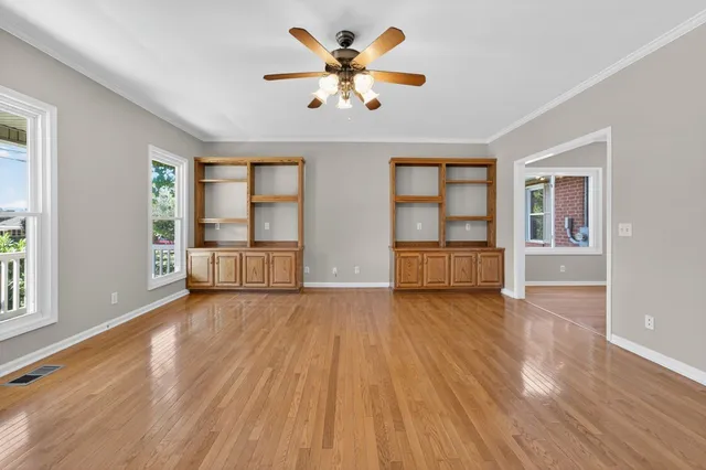 a view of an empty room with wooden floor and a window