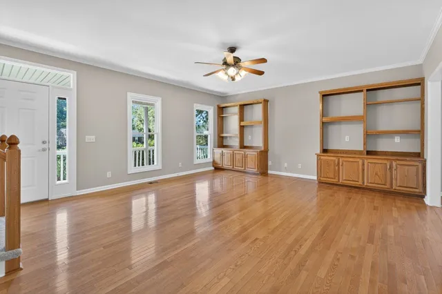 a view of an empty room with a window and wooden floor