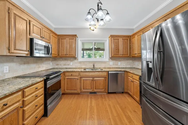 a kitchen with stainless steel appliances granite countertop a stove a sink dishwasher a refrigerator and a microwave oven