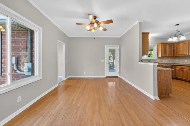 a view of an empty room with window and wooden floor