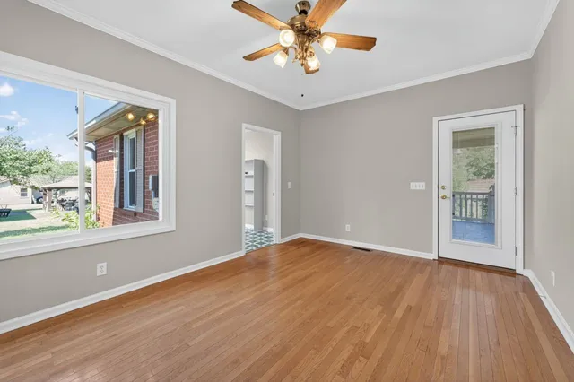 a view of an empty room with a window and wooden floor