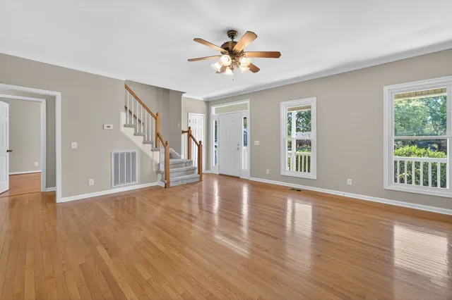a view of an empty room with wooden floor and a window