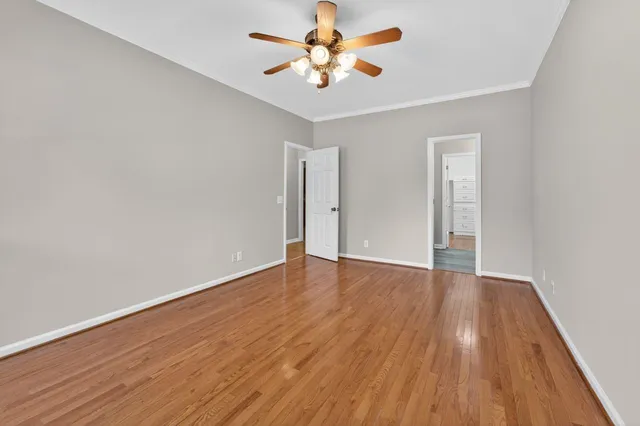 an empty room with wooden floor and a ceiling fan