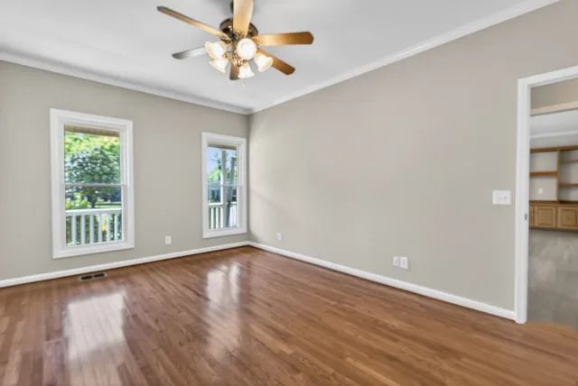 a view of an empty room with wooden floor and a window