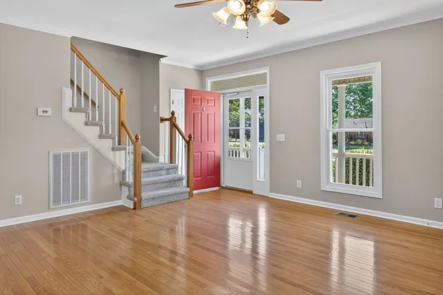 a view of an empty room with a window and wooden floor