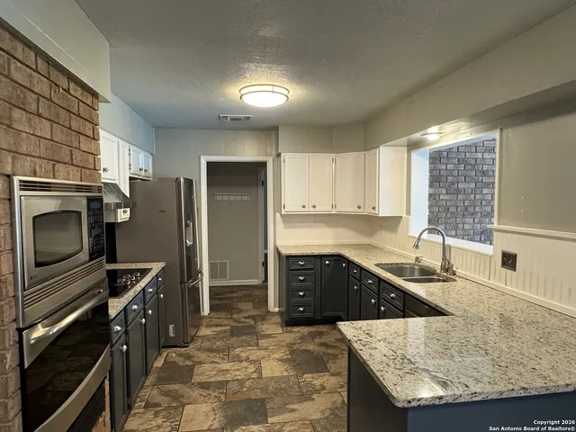 a kitchen with granite countertop a sink stove and refrigerator